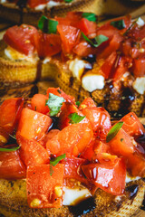 Italian Bruschetta served on a wooden plate, decorated with Basil.