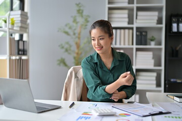 Young professional woman is rolling up her sleeves and getting ready to work on a new project in her bright, modern office