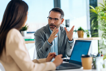 Elegant business people working together with laptop while talking in a modern office