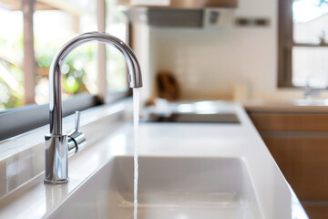 Modern white kitchen sink with clean chrome faucet with water flows
