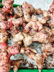 A stack of Galangal, a traditional spice widely used in Asian, especially Southeast Asian, cuisine, displayed in a traditional market stall