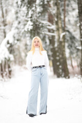 Portrait of a young beautiful blonde girl outdoors in winter in cloudy weather.