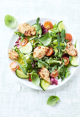 Salad with Chicken Breast, Cherry Tomatoes, Cucumber, Rocket and fresh Basil. Bright wooden background. Top view. Close up.
