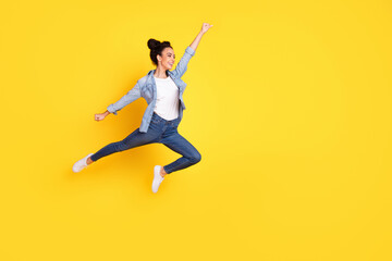 Full body portrait of nice young girl jump empty space wear denim shirt isolated on yellow color background