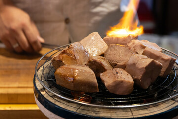 Chef cooking a sous vide beef tongue on fire.
