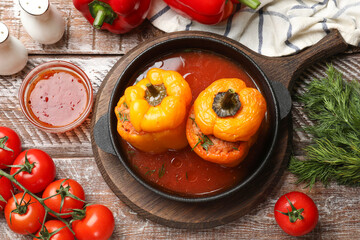 Tasty stuffed peppers in pan, sauce and products on wooden rustic table, flat lay