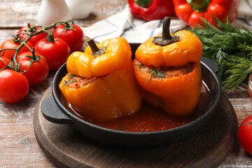 Tasty stuffed peppers in pan and products on wooden rustic table, closeup