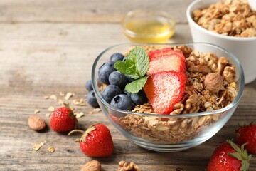Tasty granola with berries, nuts and mint on wooden table. Space for text