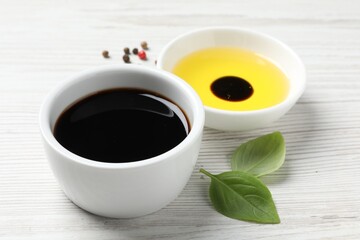 Balsamic vinegar, oil, peppercorns and basil on white wooden table