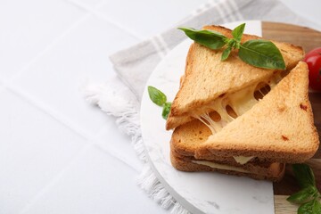 Pieces of toasted bread with melted cheese and basil on white table, space for text