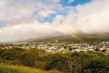 Rainbow arches across sky above distant city, blending with landscape