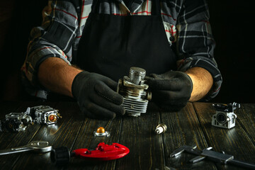 Restoring a brush cutter engine by a master. Work environment on a workshop table with spare parts...