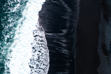 Aerial view of waves crashing on the black sand beach in Iceland, a popular tourist destination.