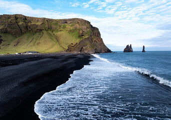 Aerial view of Reynisfjara black sand beach and sea stacks in Iceland.