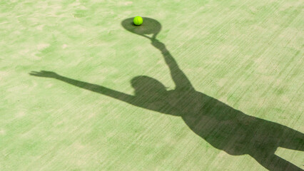 The shadow of a girl with a racket on a green tennis court.Tennis or padel