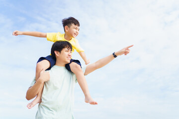 Asian father and son playing together, a man piggyback the boy on his back.