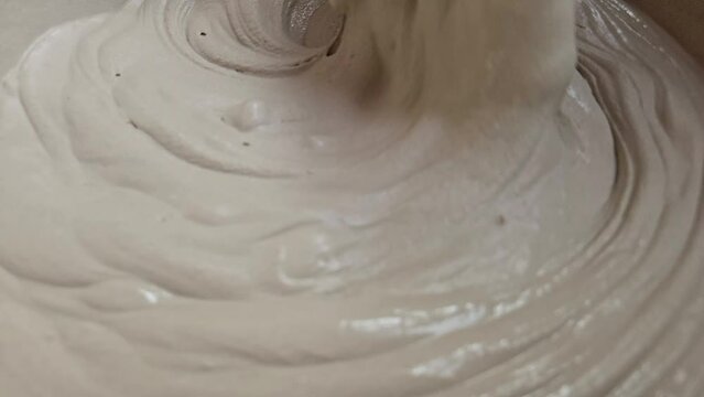 Hand Of An Sculpture Artist Mixing Plaster Of Paris And Water In A Bowl To Make Plaster Mold, India