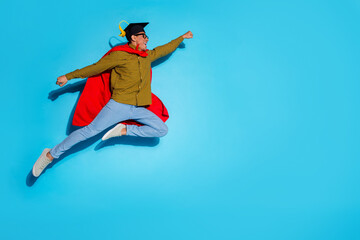 Fototapeta premium Full body photo of attractive young man flying superhero graduation dressed stylish plaid clothes isolated on blue color background