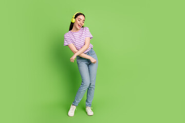 Full length photo of lovely young lady dance have fun dressed stylish striped violet garment isolated on green color background