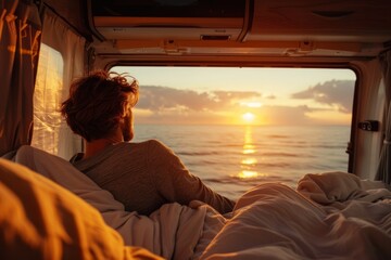 A man rests in the back of his camper van watching the sunset over the sea