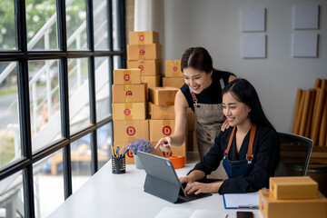 Two women are sitting at a desk with a laptop