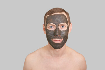Black Clay Mask on Guy Face. Cosmetology man portrait with mud healthy scrub. Coal nature eco masque. Dermatology charcoal product. Home skin care routine. Skincare male treatment. Grey