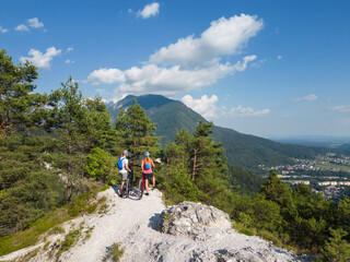 Obraz premium Two tourists cyclists on electric mountain bikes enjoying a beautiful highland landscape, aerial view.