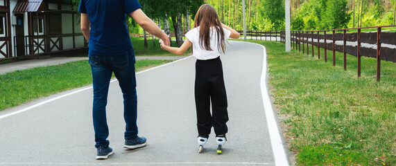 Father and daughter ride on roller skates. Girl learning to roller skate, and falls. Dad teaches...