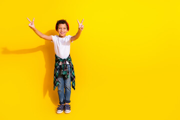Full body photo of cute little boy show v-sign dressed stylish white clothes isolated on yellow color background