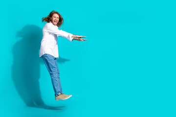 Full length photo of attractive funny guy wear white shirt jumping high emtpy space isolated blue color background