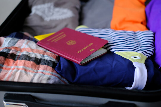 close-up of bright women's passport, covid certificate, things, folded clothes in open silvery suitcase, collecting things for vacation, business trip, an exciting journey, tourism, voyage concept