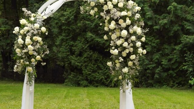 wedding arch of white rose flowers in the forest before the wedding ceremony of the bride and groom, festive romantic boho style decor