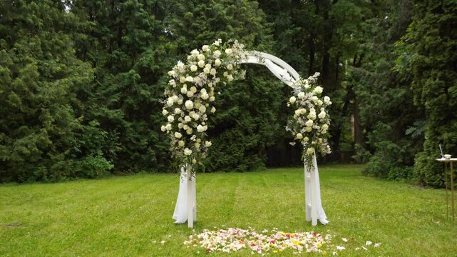 wedding arch of white rose flowers in the forest before the wedding ceremony of the bride and groom, festive romantic boho style decor