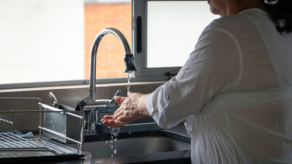 An elderly woman washing her hands