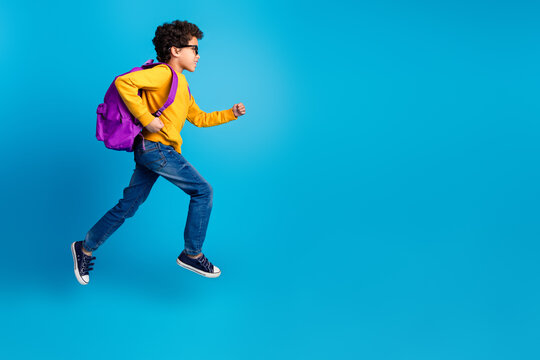 Full body photo of cute little boy carry backpack schoolkid run dressed stylish yellow clothes isolated on blue color background - Powered by Adobe