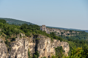 Medieval ruins perched on rocky cliffs overlooking lush green valley