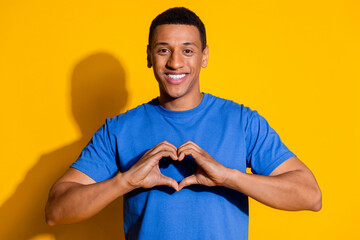 Photo portrait of handsome young guy show heart gesture dressed stylish blue garment isolated on...