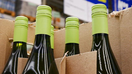 Close-up of a few wine bottles with green caps in a trading box