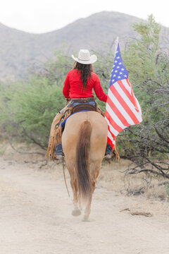 Cowgirl on her Mustang horse with the US flag