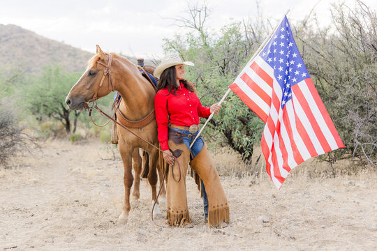 Cowgirl with her Mustang horse holding the US flag
