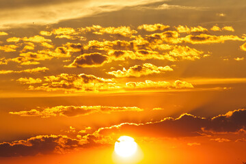 Sunset Sky and Sun in the Evening with Orange, yellow sunlight on Golden hour sky, Dramatic storm Clouds Summer background.