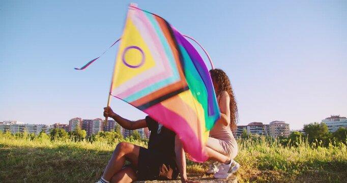diverse and inclusive friends enjoy and having fun outisde waving LGBT flag whit empowerment in slowmotion ang gimbal camera movement whit the city on the background. Supporting LGBT Pride Together
