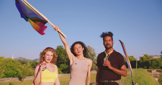 trans woman rise and wave LGBT flag new progress whit friends to celebrate gay pride parade day of unity , love and diversity