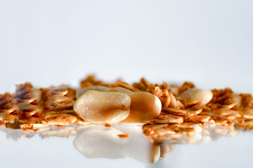 Pile of granola with peanut pieces. White background and glass reflection.Copy space