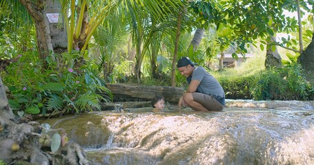 A father and young child enjoying a moment together Exploring bonding in a shallow tropical stream in Forest on a Sunny Day surrounded by lush greenery and natural beauty, Refreshing Tropical Stream