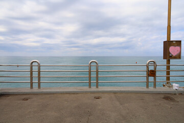 View of the sea, horizon over water with the pier and metal railing in the foreground.  Taken in Forte dei Marmi Italy.