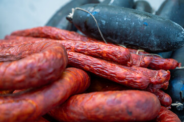 portuguese traditional sausages, chorizo, sausage and black pudding, The image shows red chorizo and dark blood sausages on a metal plate,  ready for grilling.
