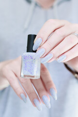 Female hand with long nails and a white gray and purple manicure