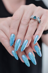 Woman's beautiful hand with long nails and light blue manicure