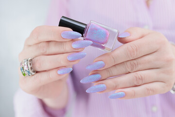 Woman hands with long nails manicure and light blue lilac pink nail polish